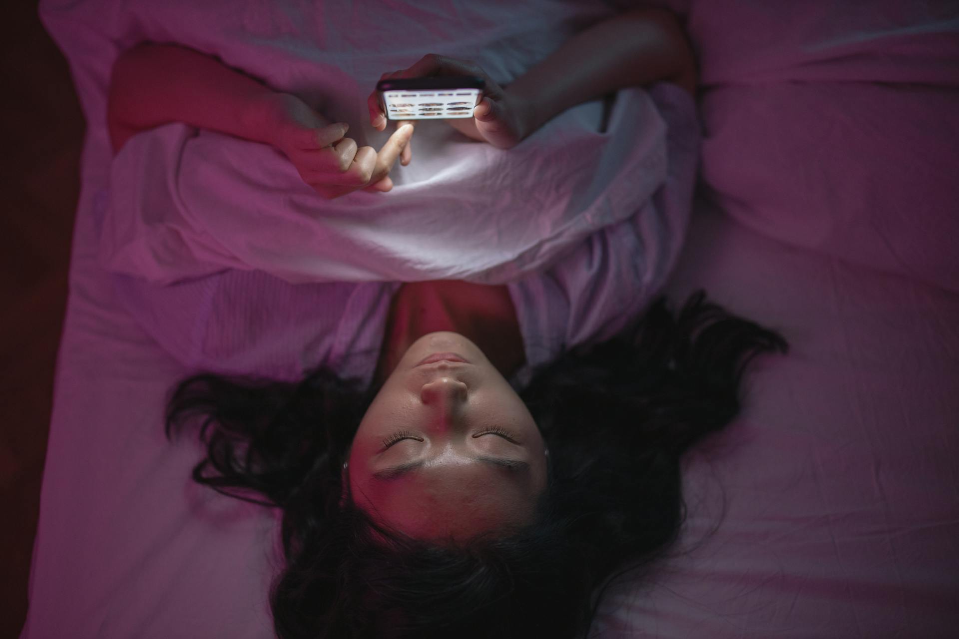 Person scrolling phone in bed