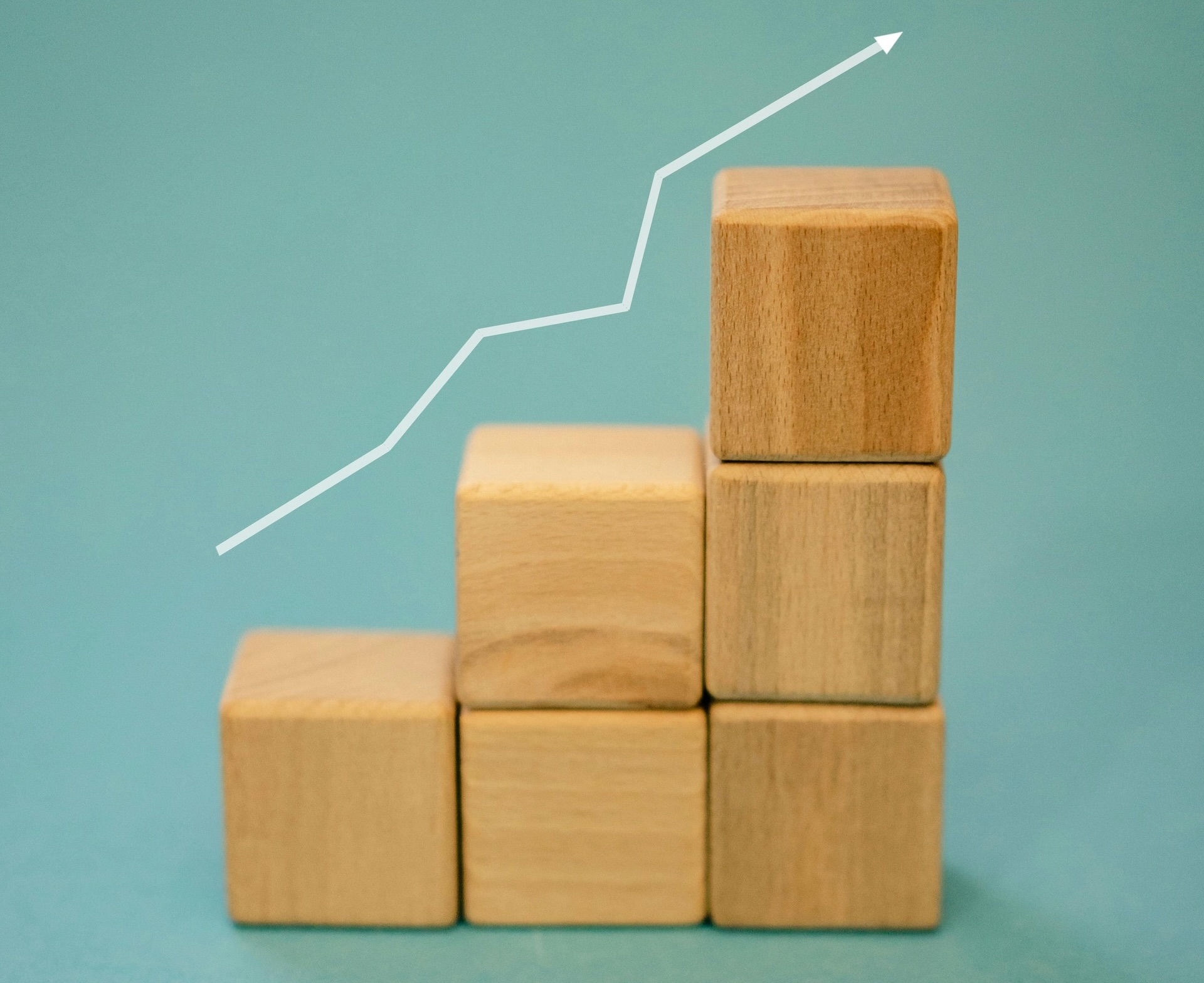 Wooden blocks forming a staircase with an upward arrow symbolizing progress